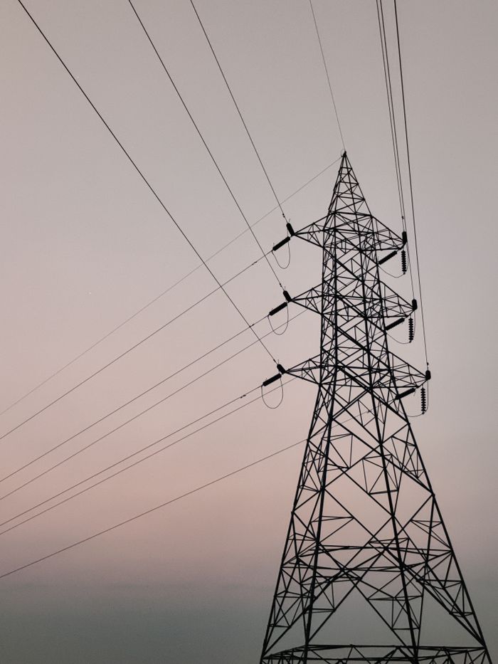 A towering transmission tower against a sunset sky, symbolizing energy and electricity.